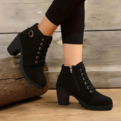 Black lace-up ankle boots with metal eyelets, worn view